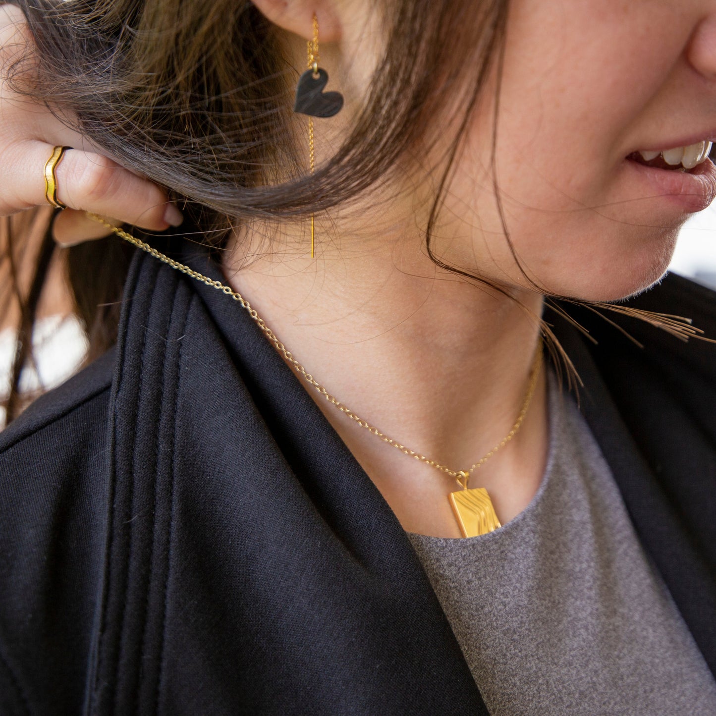 Close-up of a person wearing a gold necklace with a rectangular pendant.